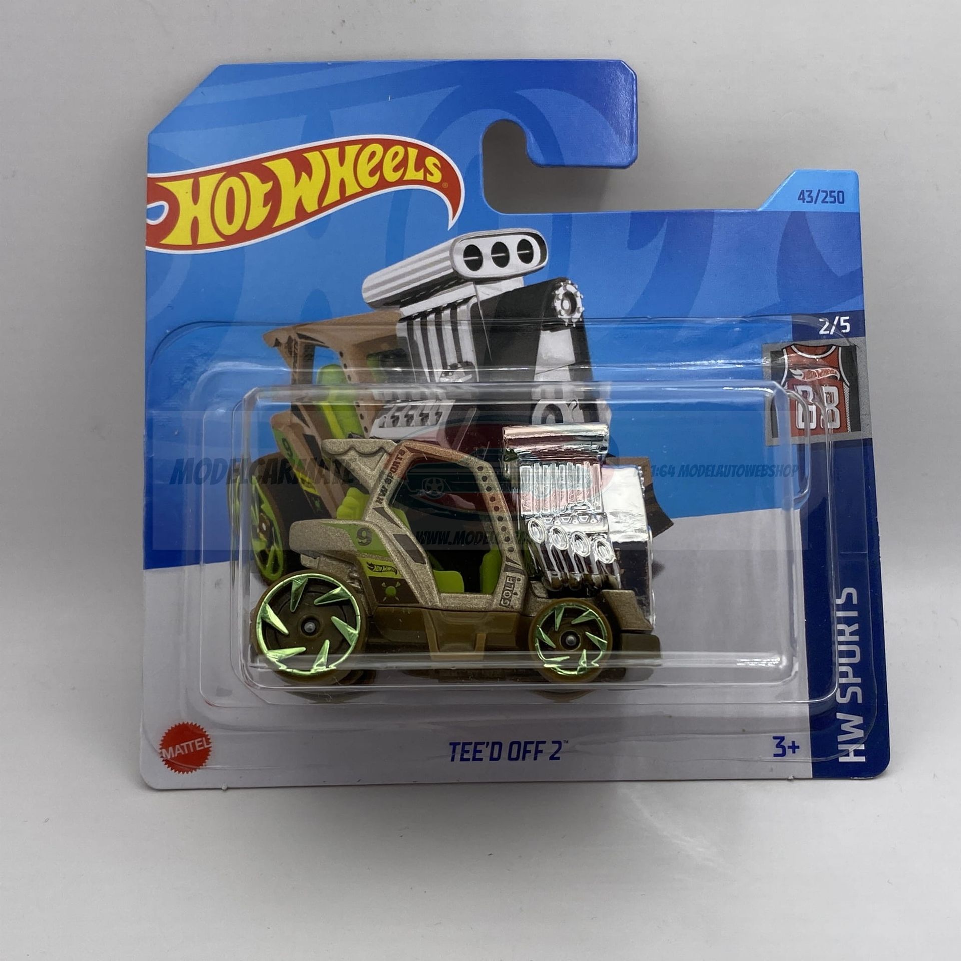 Hot Wheels "Tee'd Off" speelgoedauto in verpakking. Beige en groen, met grote motor en groene wielen.