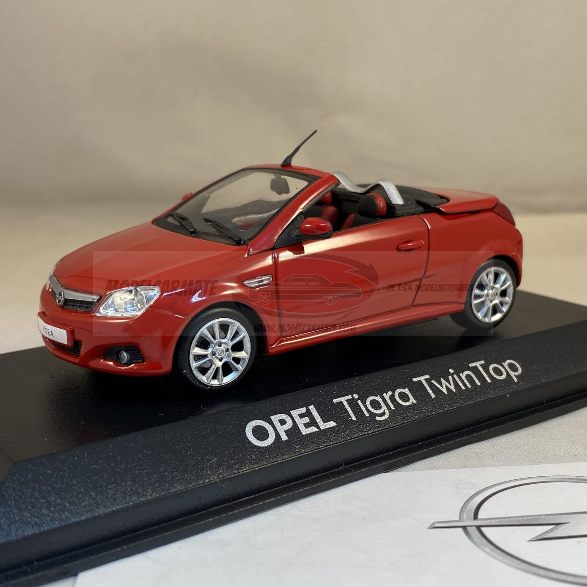 Rode Opel Tigra TwinTop cabriolet modelauto op een zwarte displaystandaard.