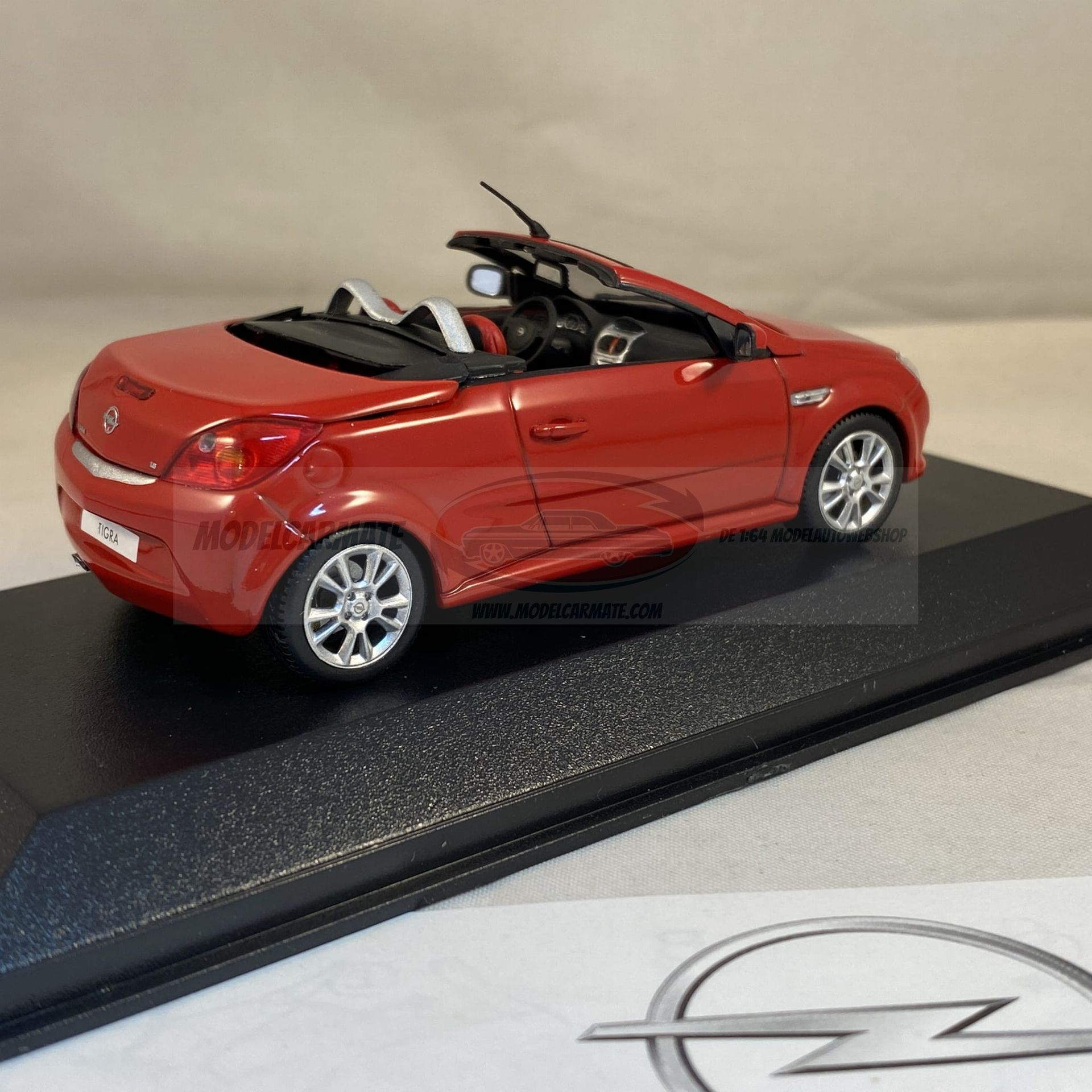 Rode Opel Tigra TwinTop cabriolet modelauto op een zwarte displaystandaard.