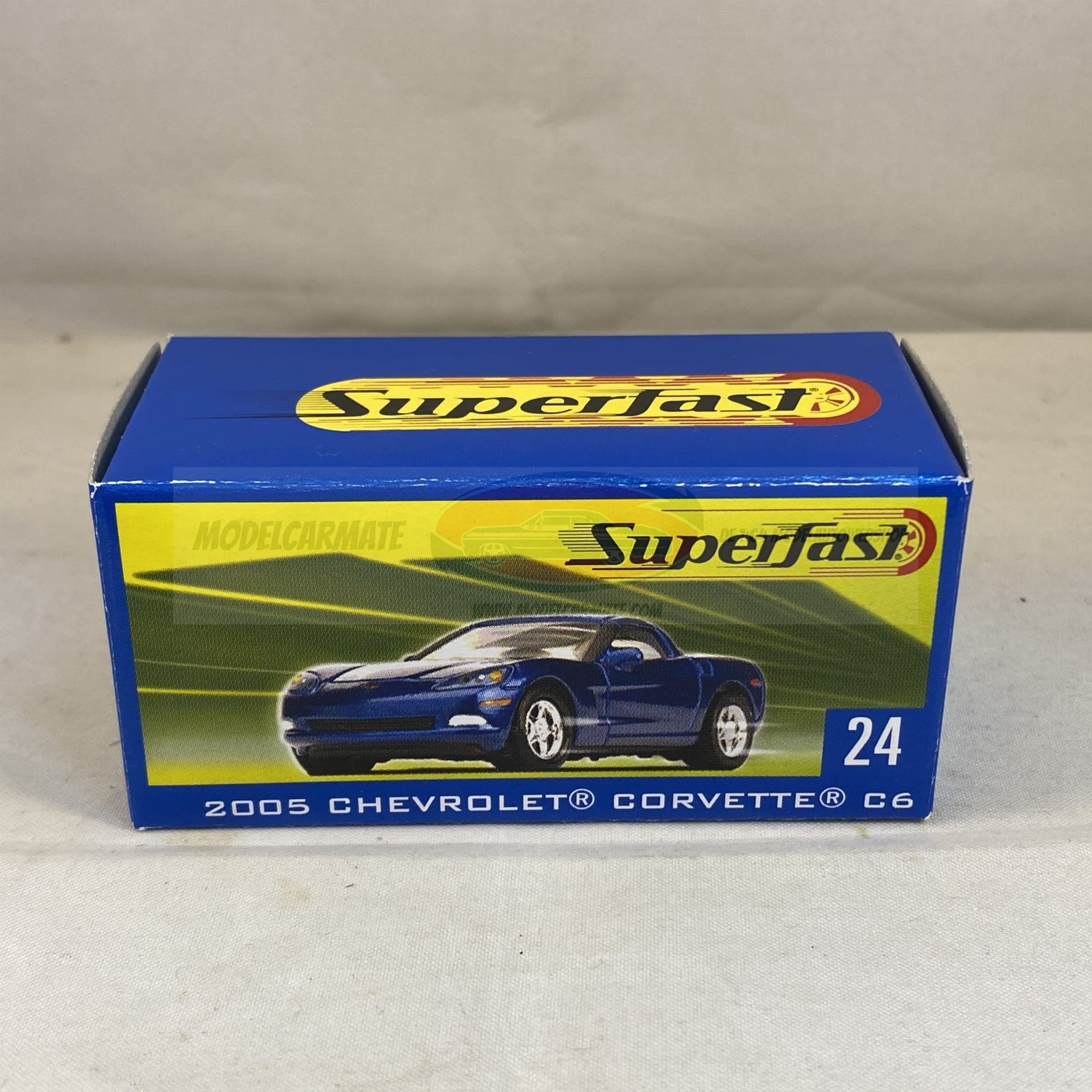Doos met een blauwe Superfast speelgoedauto, met daarop een blauwe Chevrolet Corvette uit 2003.
