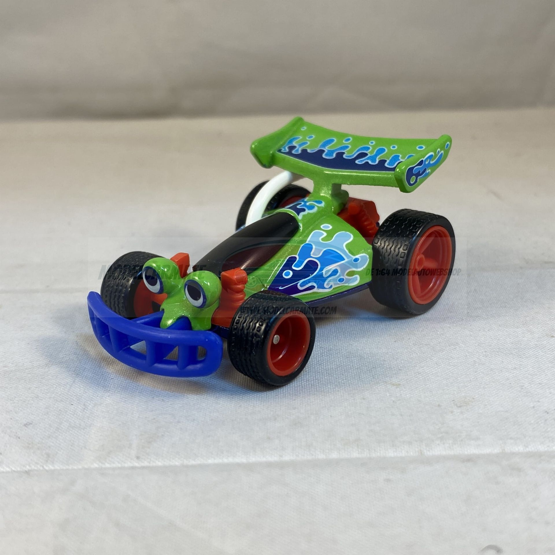 Groene speelgoedauto met kikkerachtige kenmerken, blauwe accenten en een achterspoiler.
