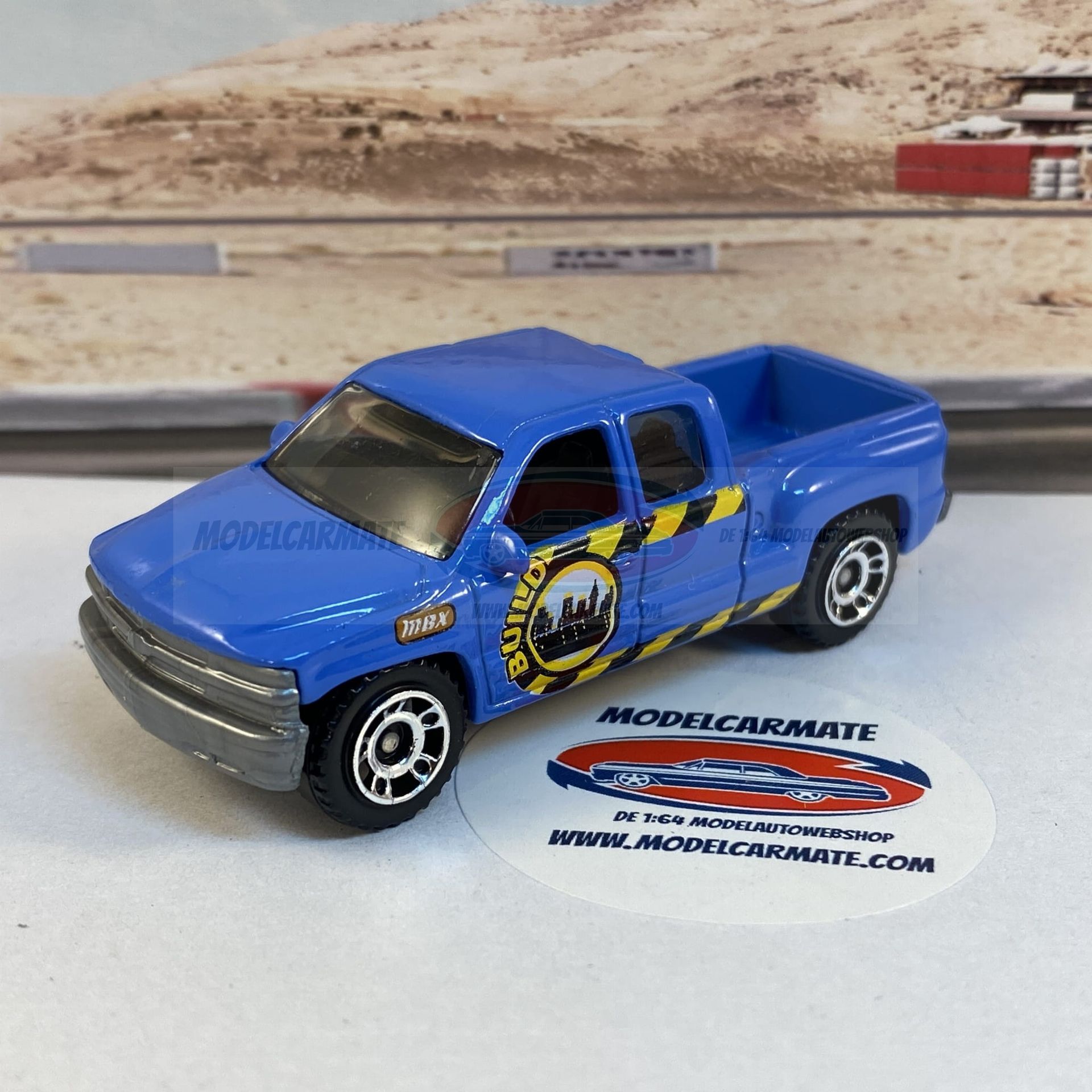 Blauwe speelgoedpick-uptruck met stadslogo op een witte ondergrond, wazige achtergrond.