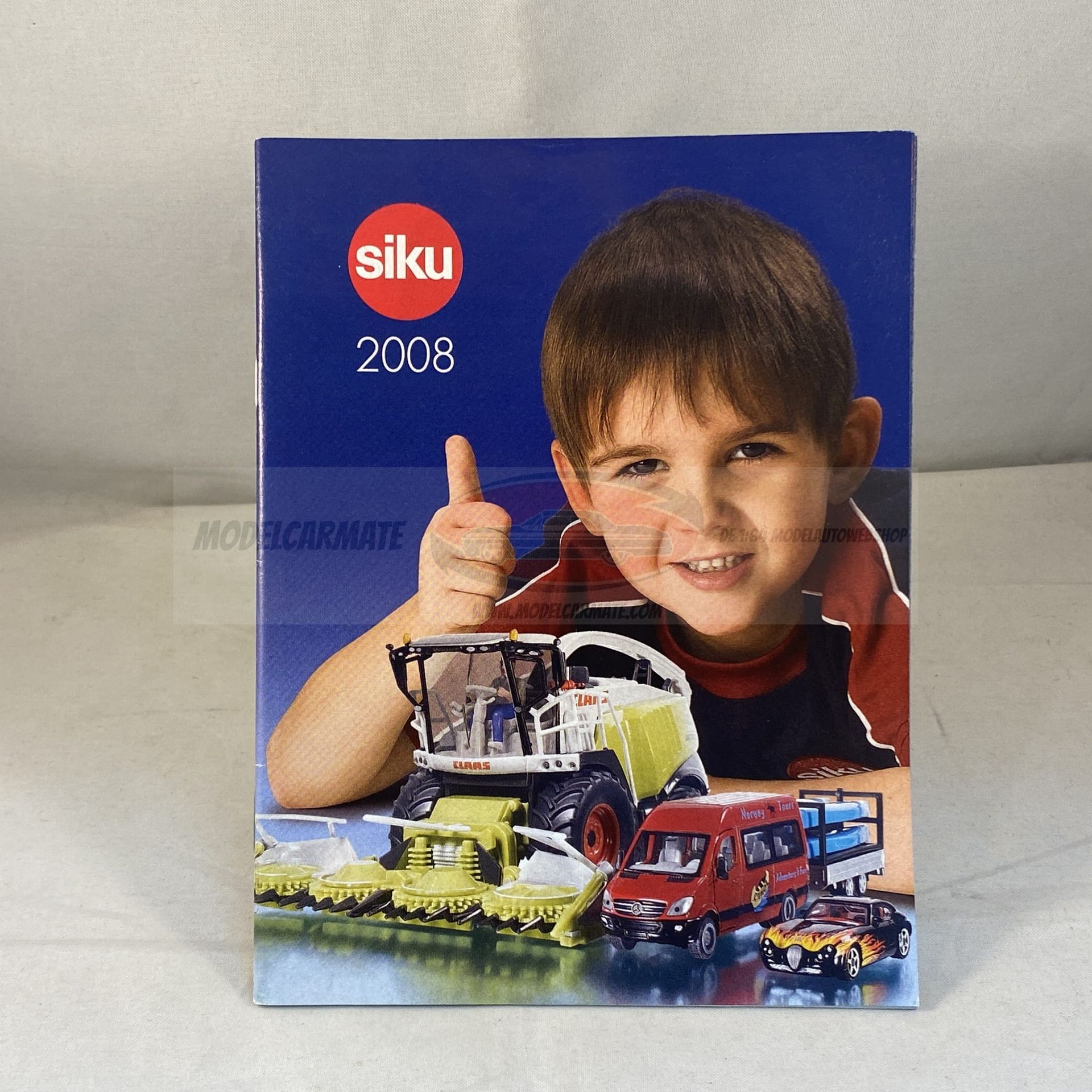 De omslag van de Siku-speelgoedcatalogus uit 2008 toont een lachende jongen, landbouwmachines en voertuigen.