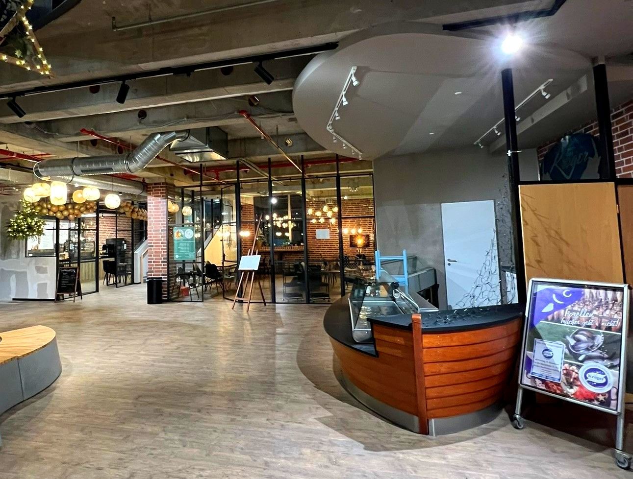 Modernes Restaurantinterieur mit Holzböden, sichtbaren Balken, warmer Beleuchtung und einer geschwungenen Theke