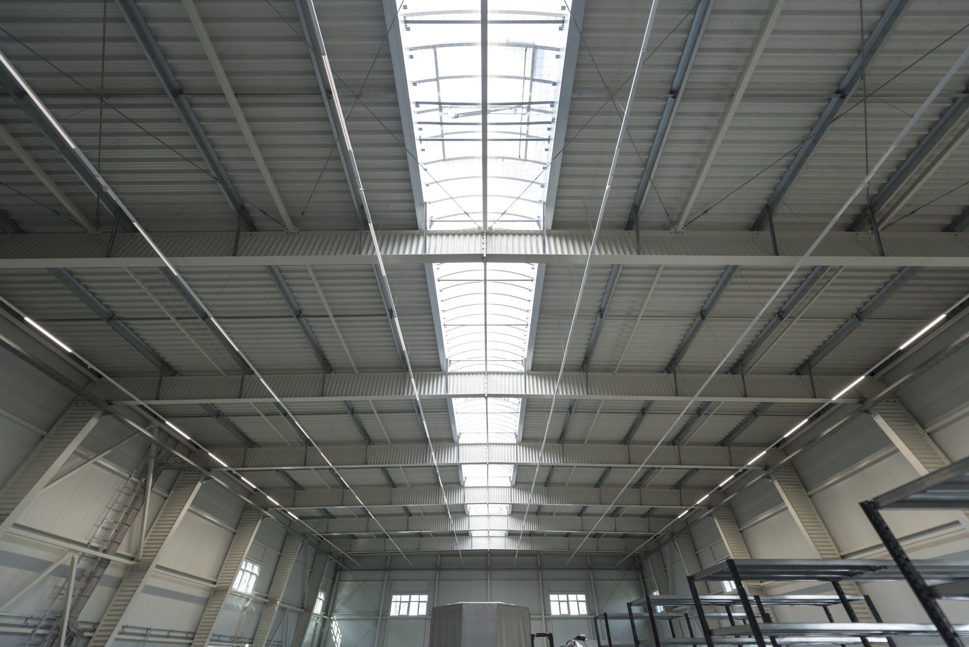 Innenansicht einer großen Industriehalle mit hohem Metalldach und Oberlichtband.