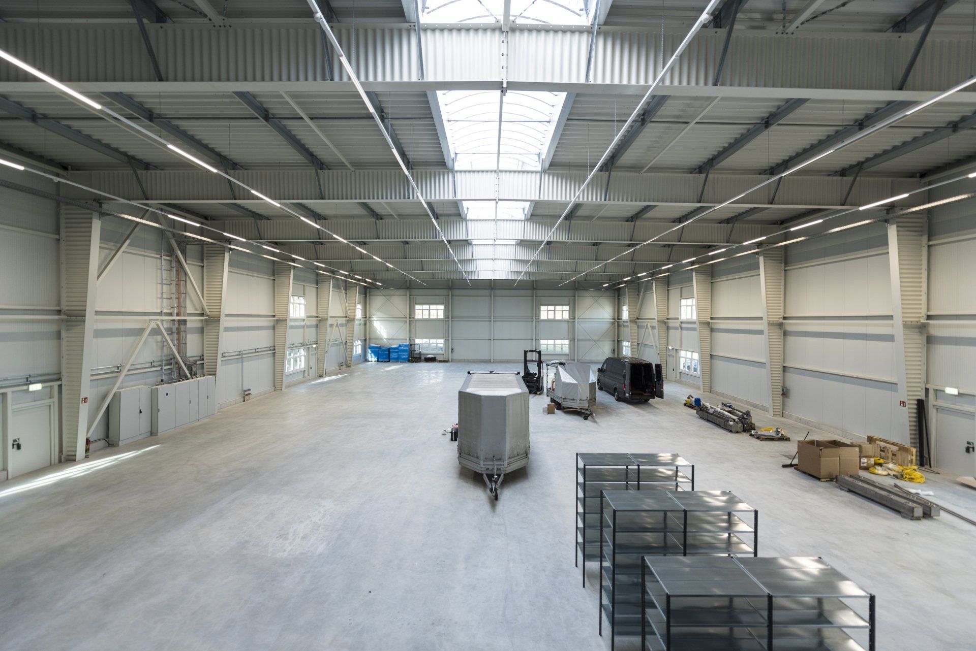 Leeres Industrielager mit Betonboden, Metallregalen und Oberlichtern.