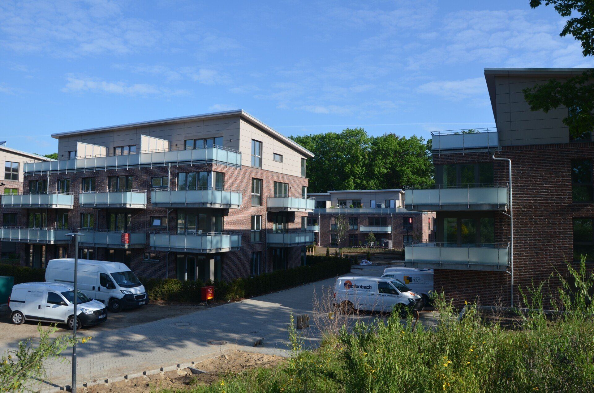 Moderner Apartmentkomplex mit Balkonen, geparkten Autos und blauem Himmel