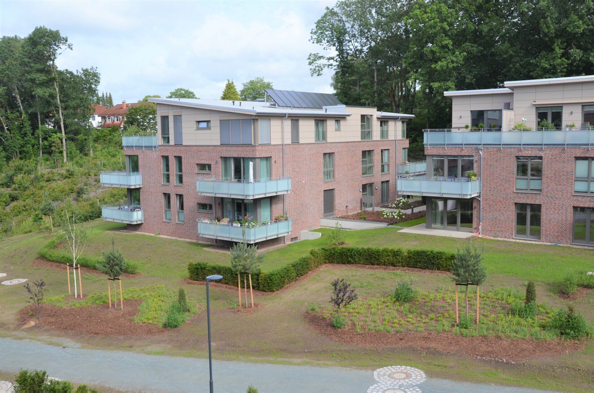 Moderne Backstein-Apartmentgebäude mit Balkonen inmitten von Grünanlagen unter einem bewölkten Himmel