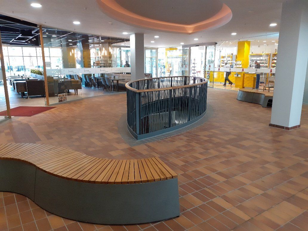Modernes Restaurantinterieur mit geschwungenen Sitzbänken, rundem Geländer und Fliesenboden unter warmem Licht