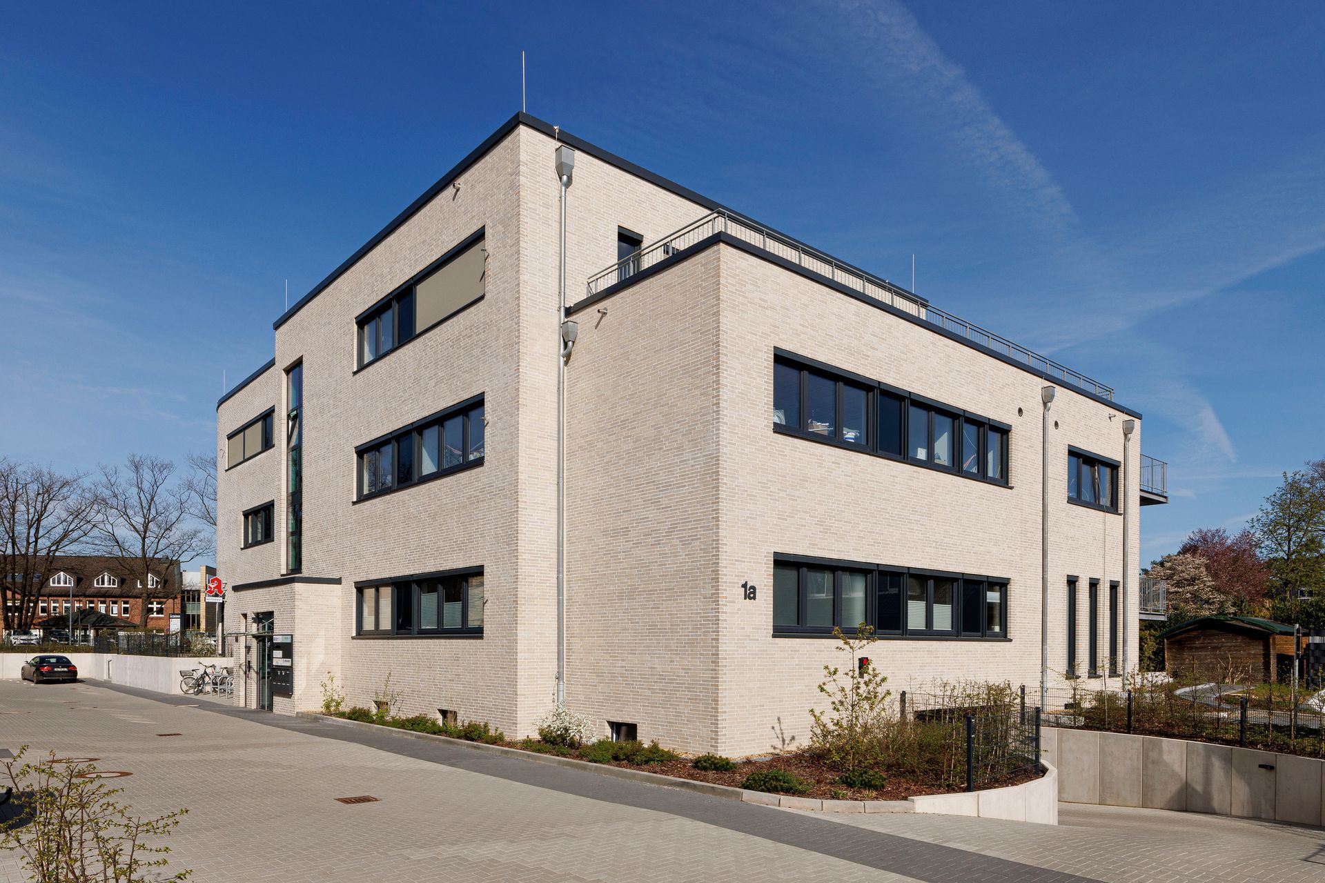 Modernes weißes Bürogebäude mit dunklen Fenstern an einer sonnigen Straßenecke