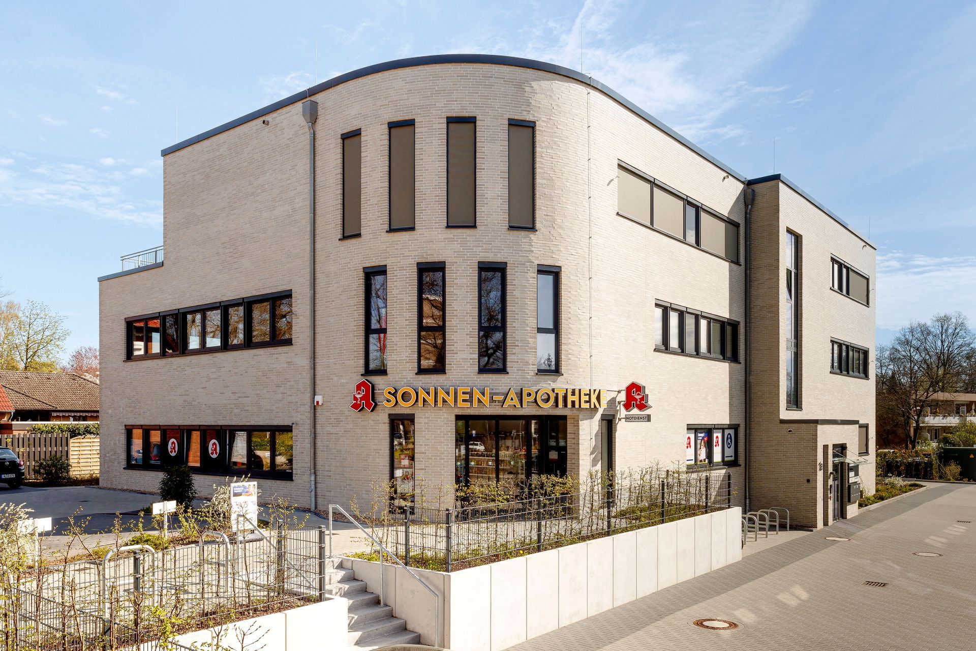 Modernes weißes Geschäftsgebäude mit großen Fenstern und Balkonen an einer Straßenecke