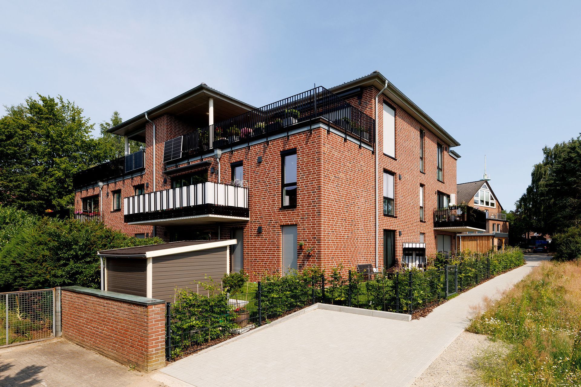 Modernes Backstein-Reihenhaus mit Balkonen an einem ruhigen Weg im Grünen