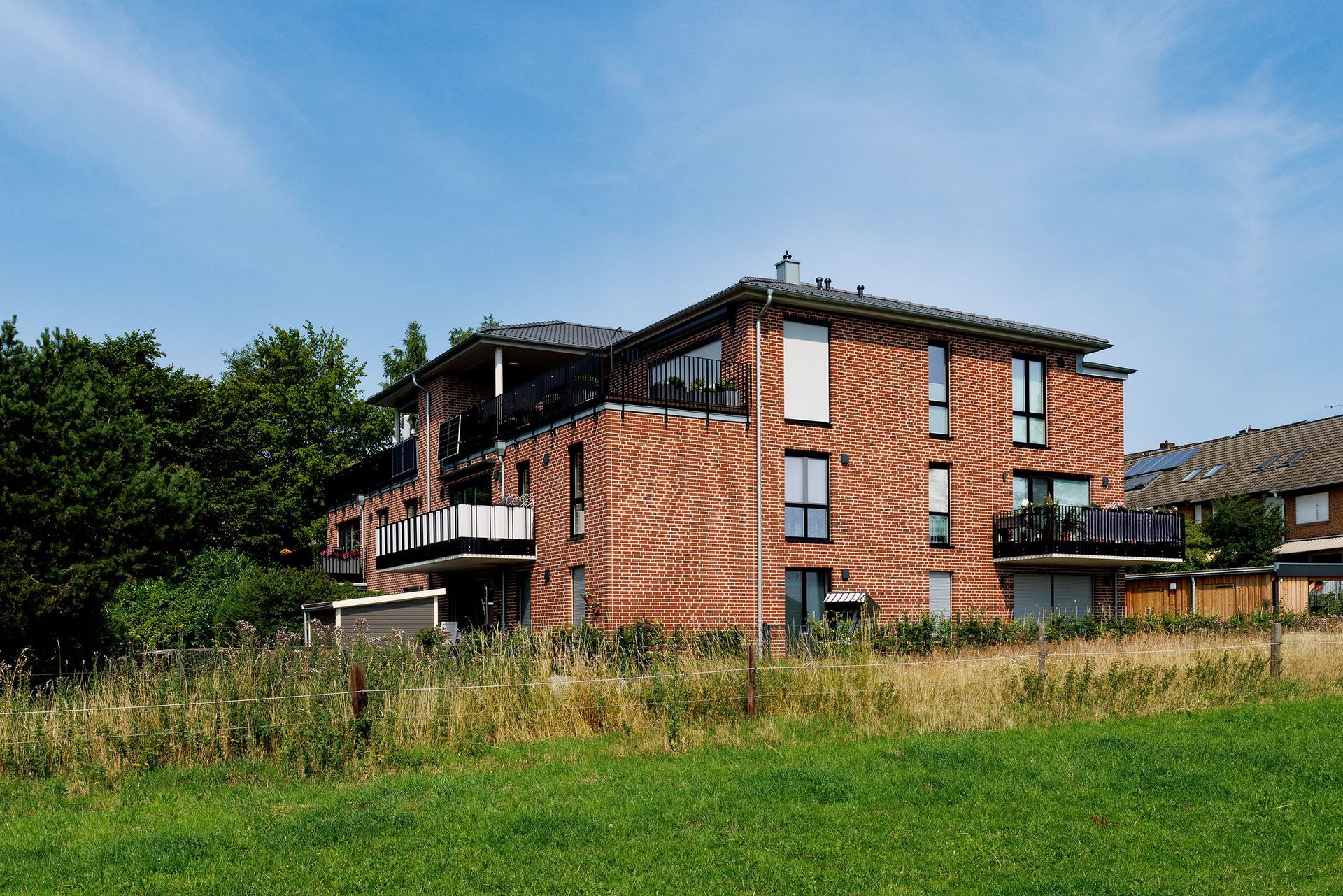 Backstein-Wohnhaus neben einer Wiese unter blauem Himmel