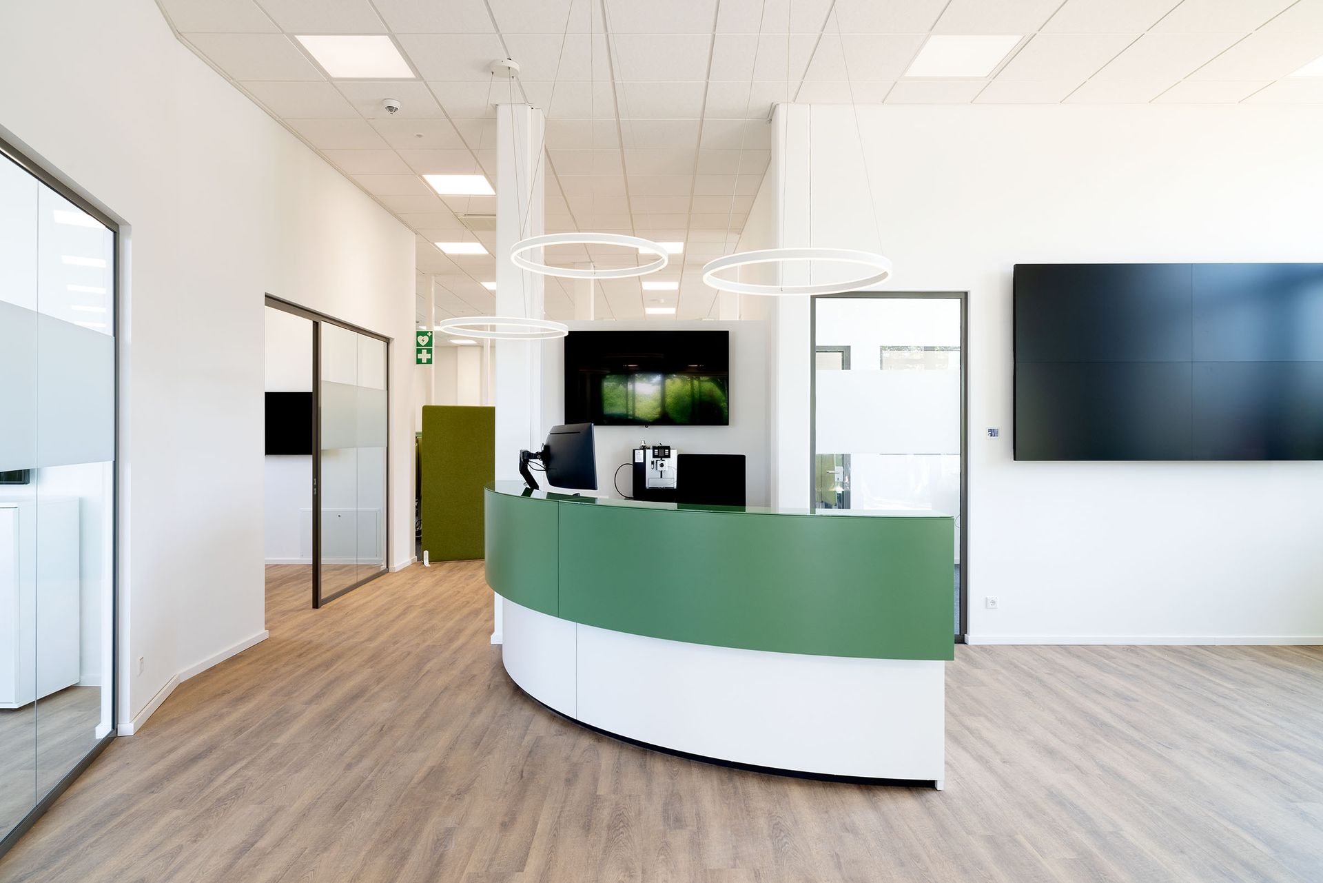 Moderner Büroempfangsbereich mit grünem Empfangstresen, Wandtrennwänden und Holzboden