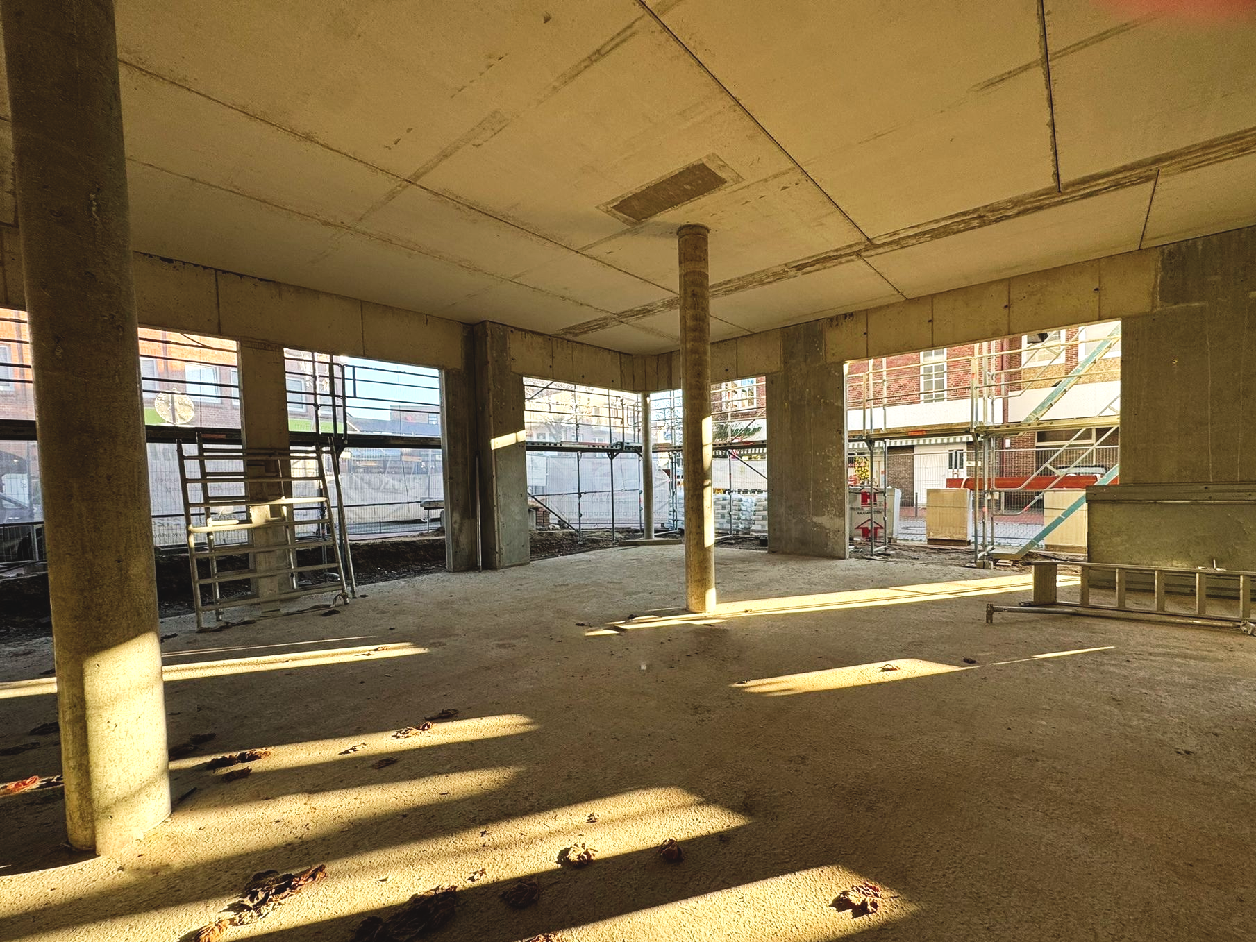 Leeres, unfertiges Betongebäude mit Säulen, durch dessen offene Seiten Sonnenlicht strömt