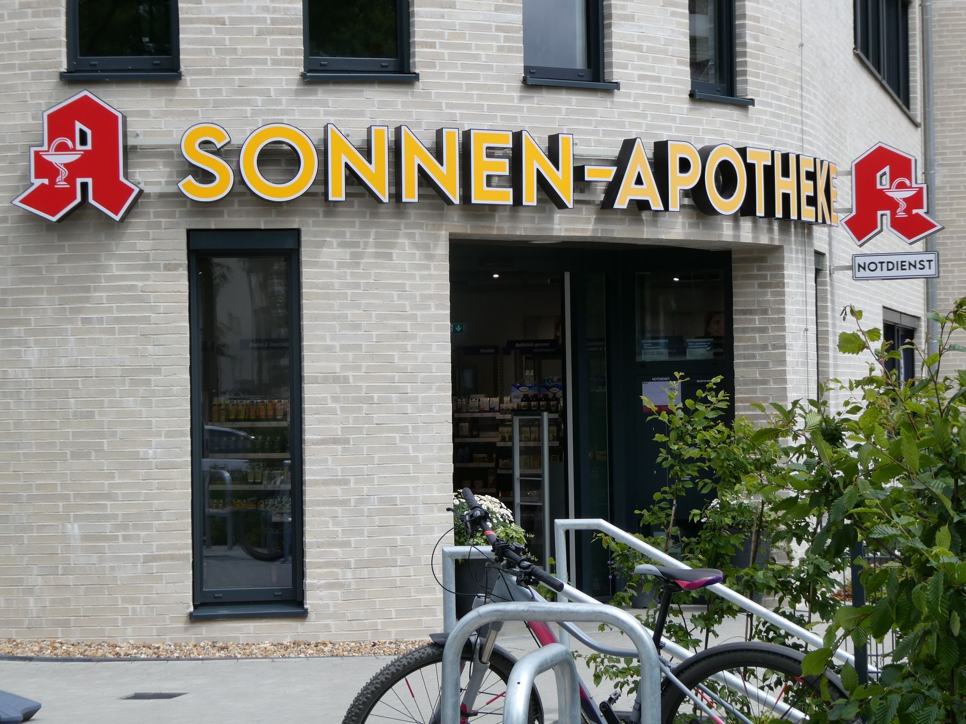 Schaufenster der Sonnen-Apotheke mit gelbem Schild und davor geparkten Fahrrädern.