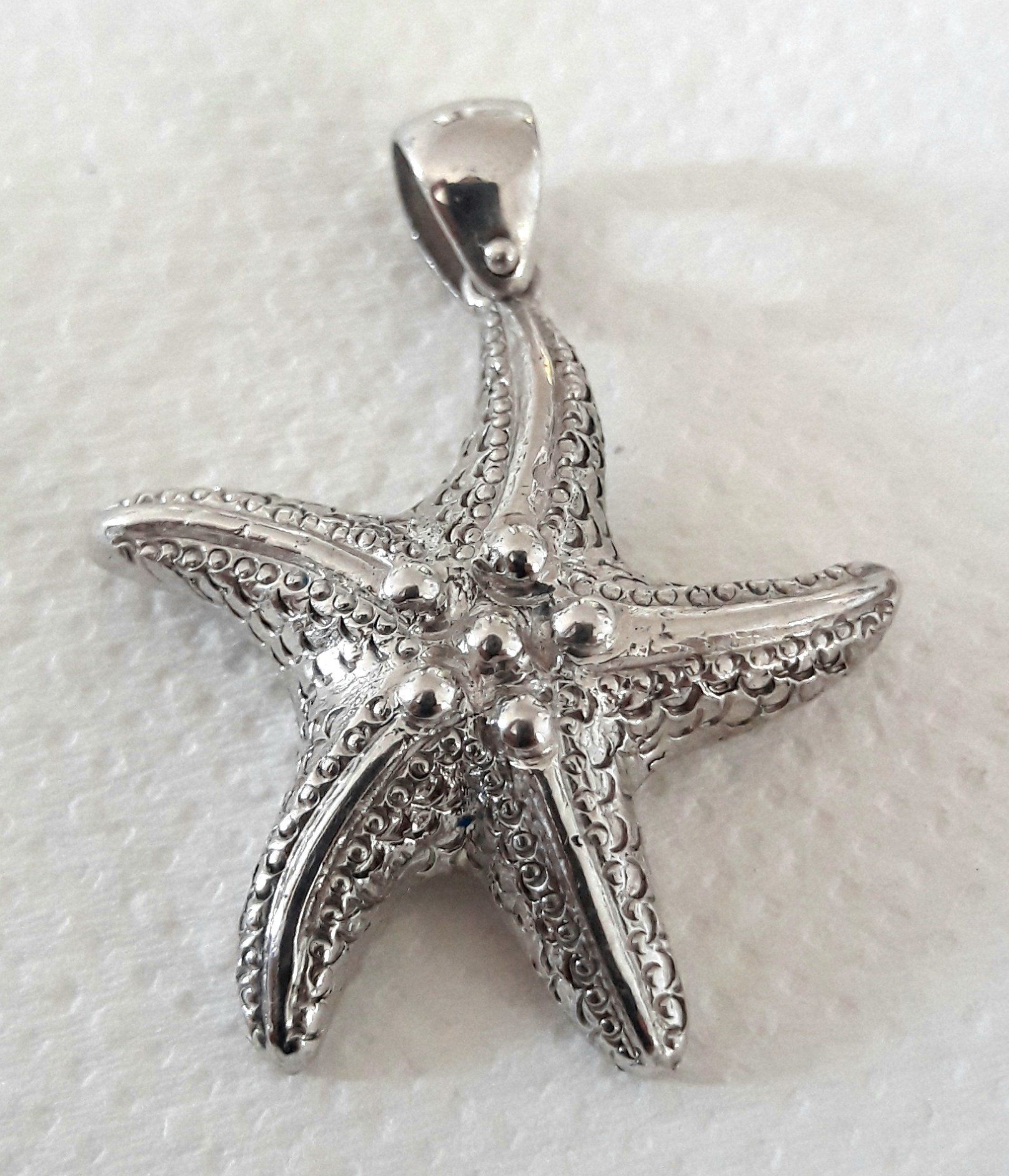 Silver starfish pendant on a white surface.