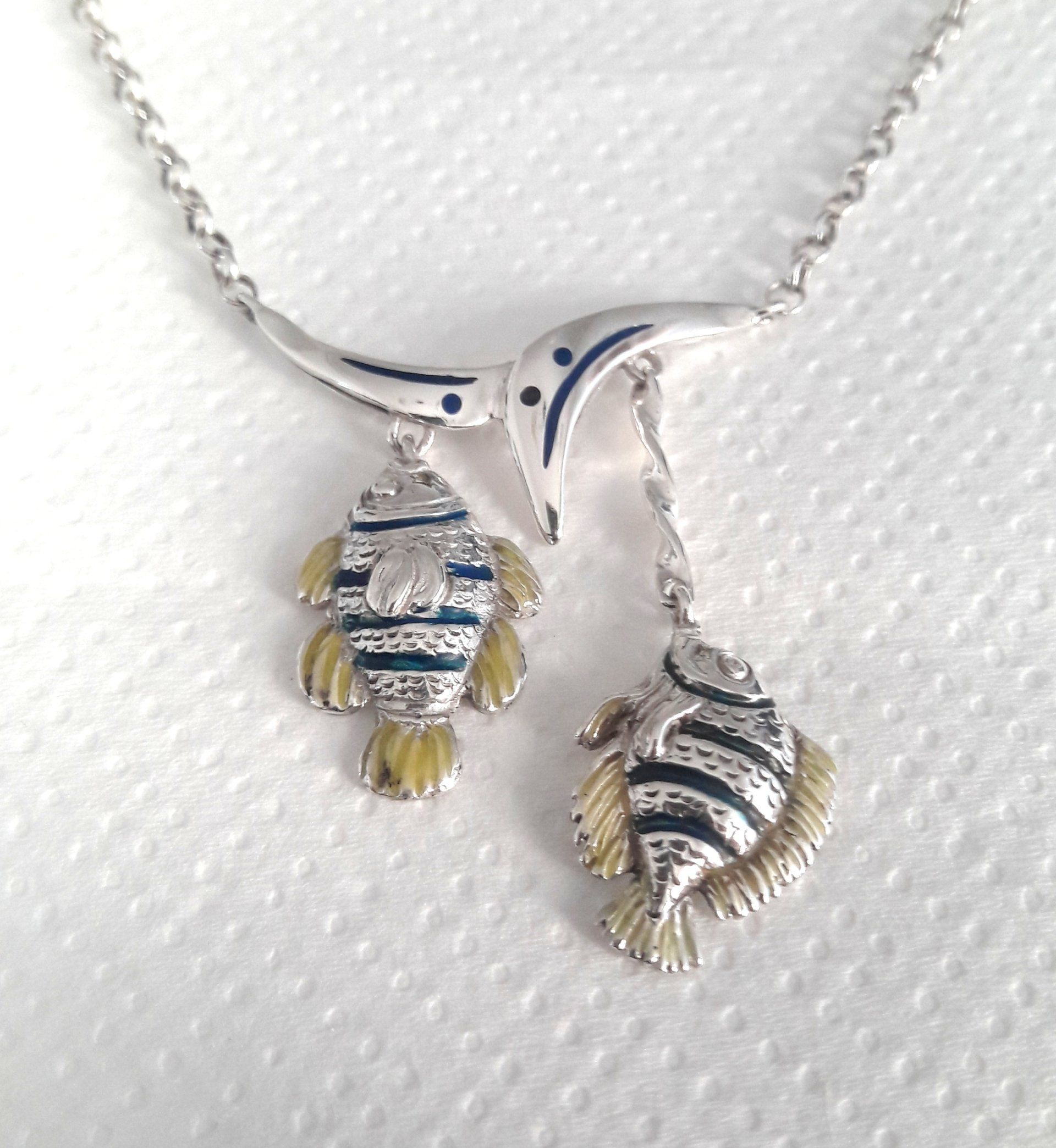 Silver necklace with two fish pendants, blue, yellow, and white enamel detailing.