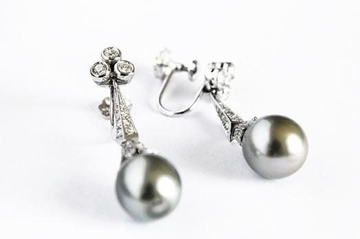 Pair of grey pearl drop earrings with diamond accents on white background.