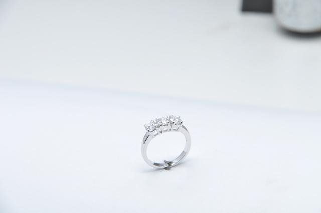 Silver ring with three clear stones on a white background.