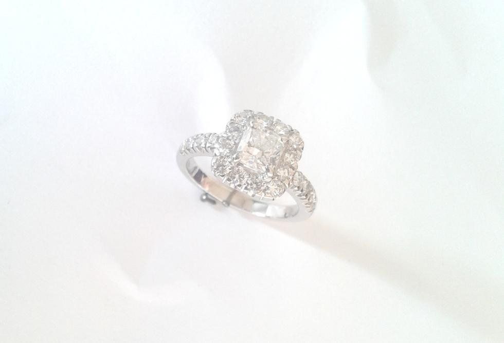 Diamond ring with a heart-shaped center stone and halo, set on a white fabric.