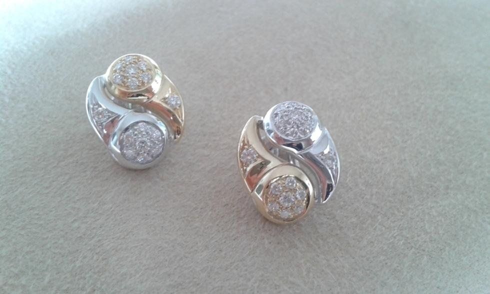 Two jeweled earrings; one gold and white, one silver and white, on a neutral surface.