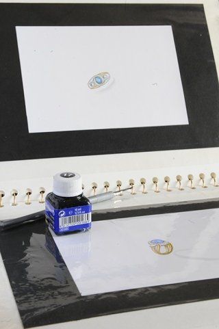 Ink bottle, pen, and drawings of jewelry on white paper.