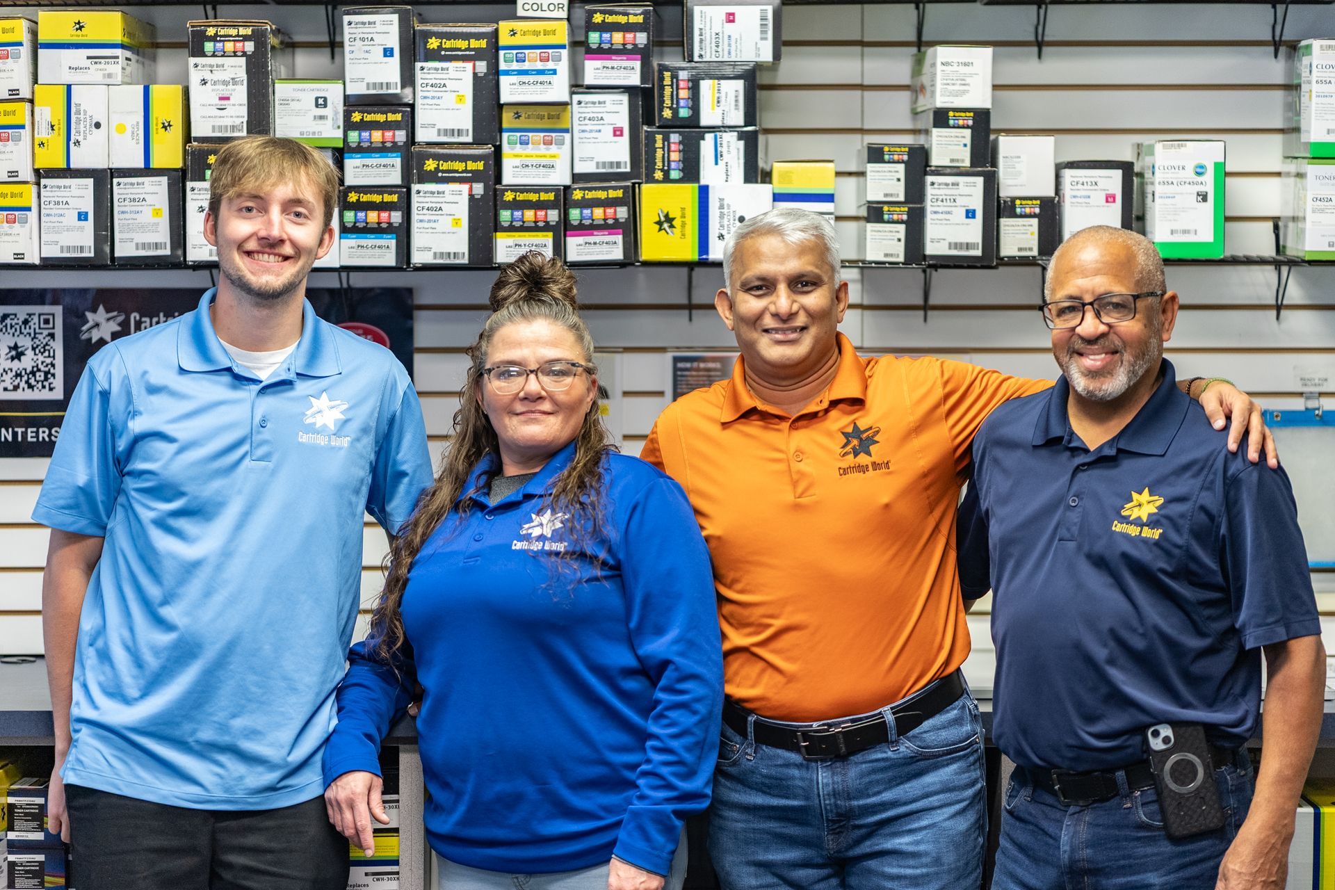 Four people, possibly employees, pose inside a Cartridge World store.