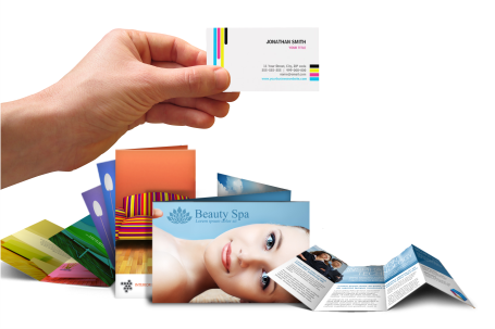 Hand holding business card, several brochures with colorful images stacked below.