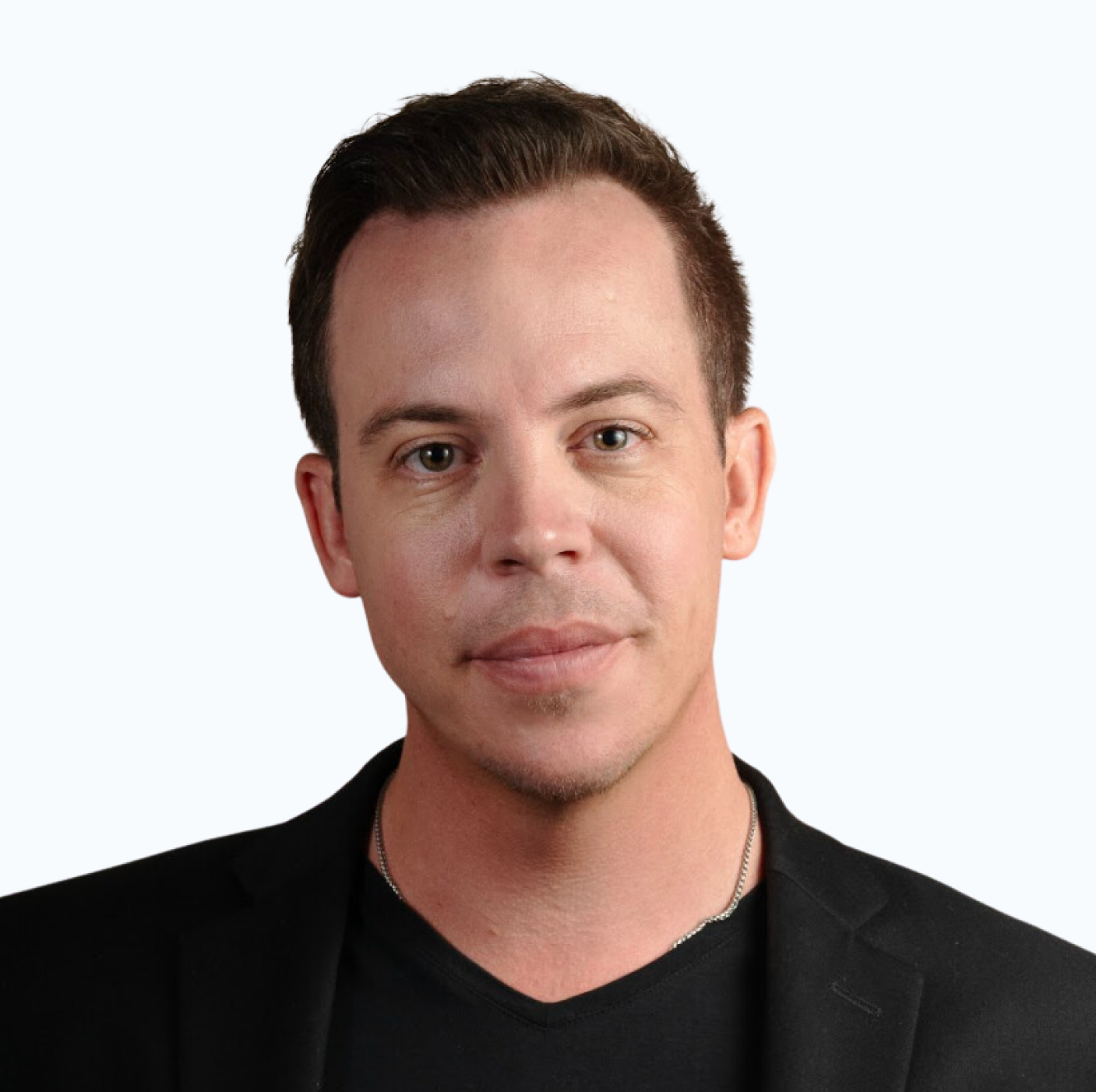 Man in a black blazer and v-neck shirt, looking at the camera.