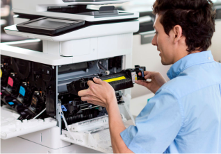 Man in a blue shirt replacing a yellow toner cartridge in a printer.