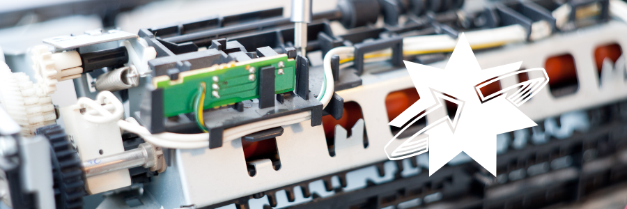 Close-up of disassembled printer internals. The focus is on a circuit board and gears.