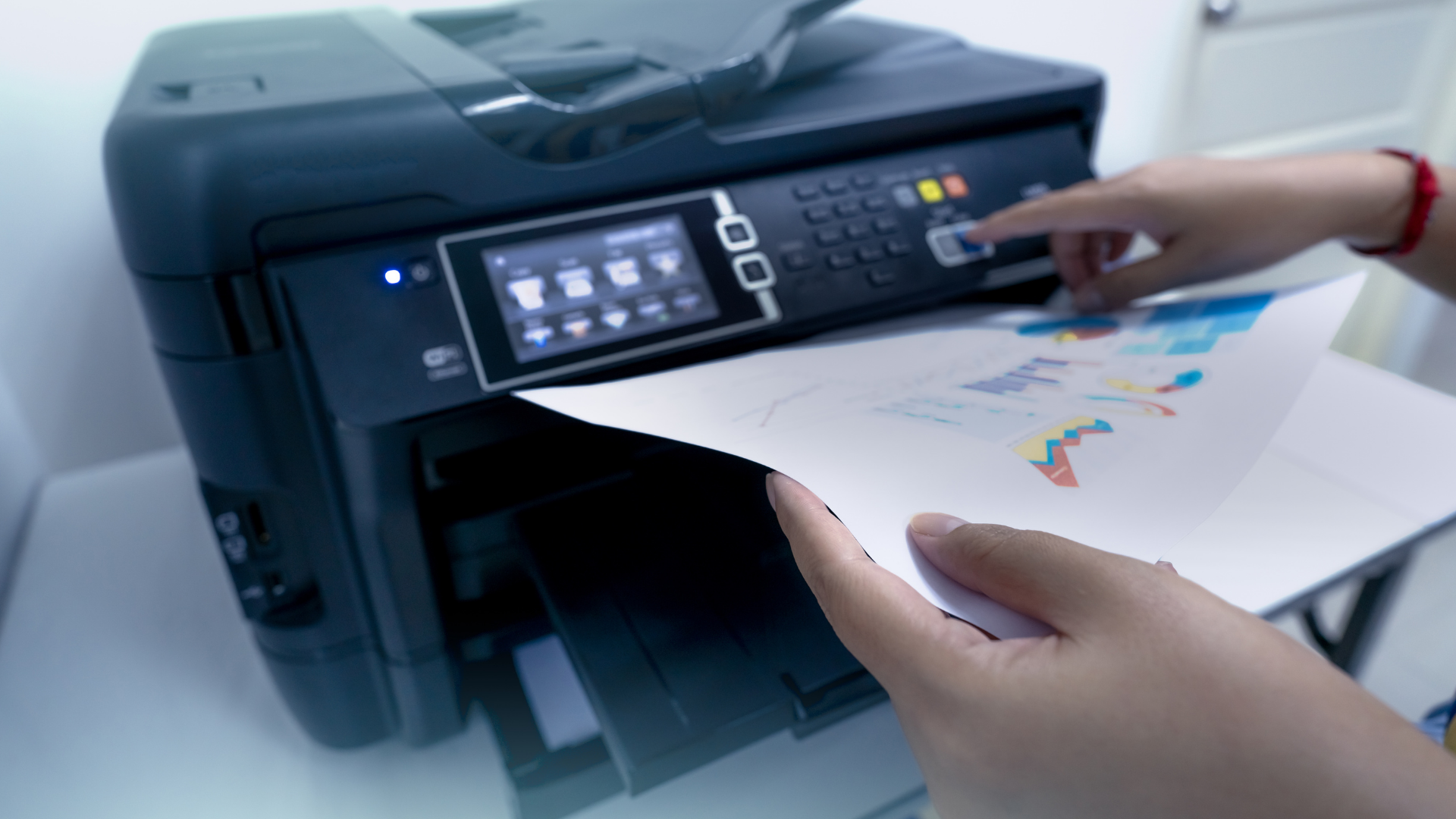 Person printing a document with colorful charts on a multifunction printer.