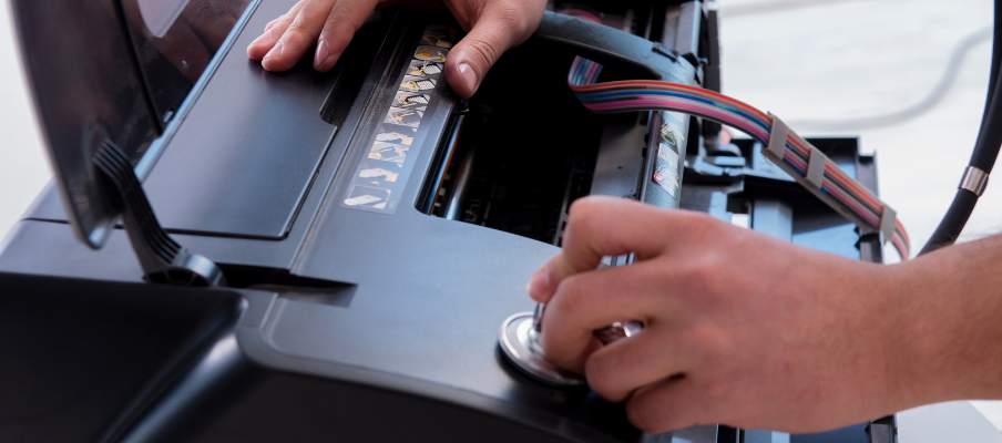 Person repairing a printer, holding a stethoscope to it.