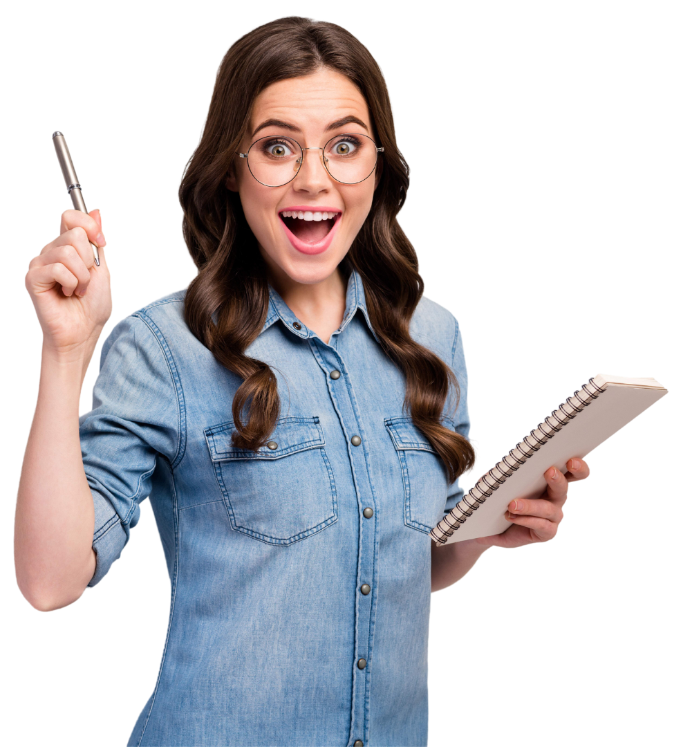 Woman with glasses, excited expression, holding pen up and notebook, wearing denim shirt.