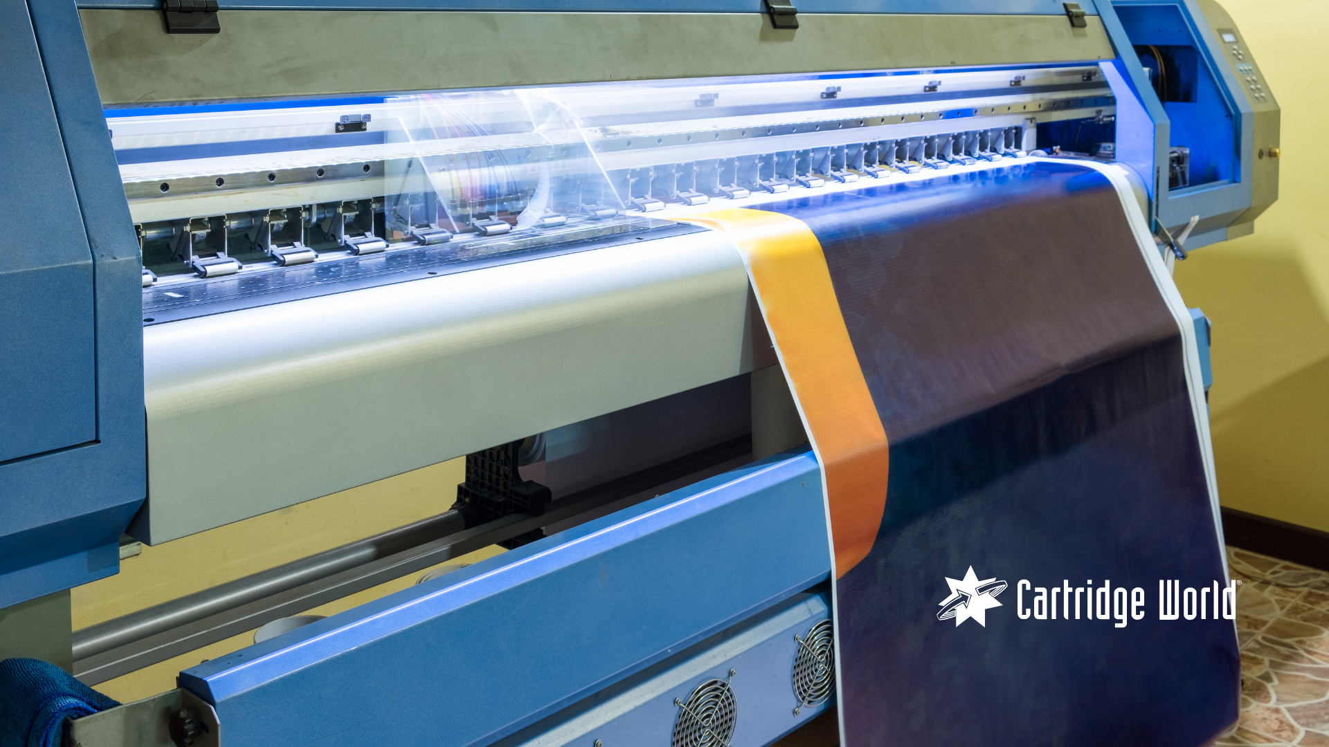 Large format printer printing a dark blue banner with an orange stripe.