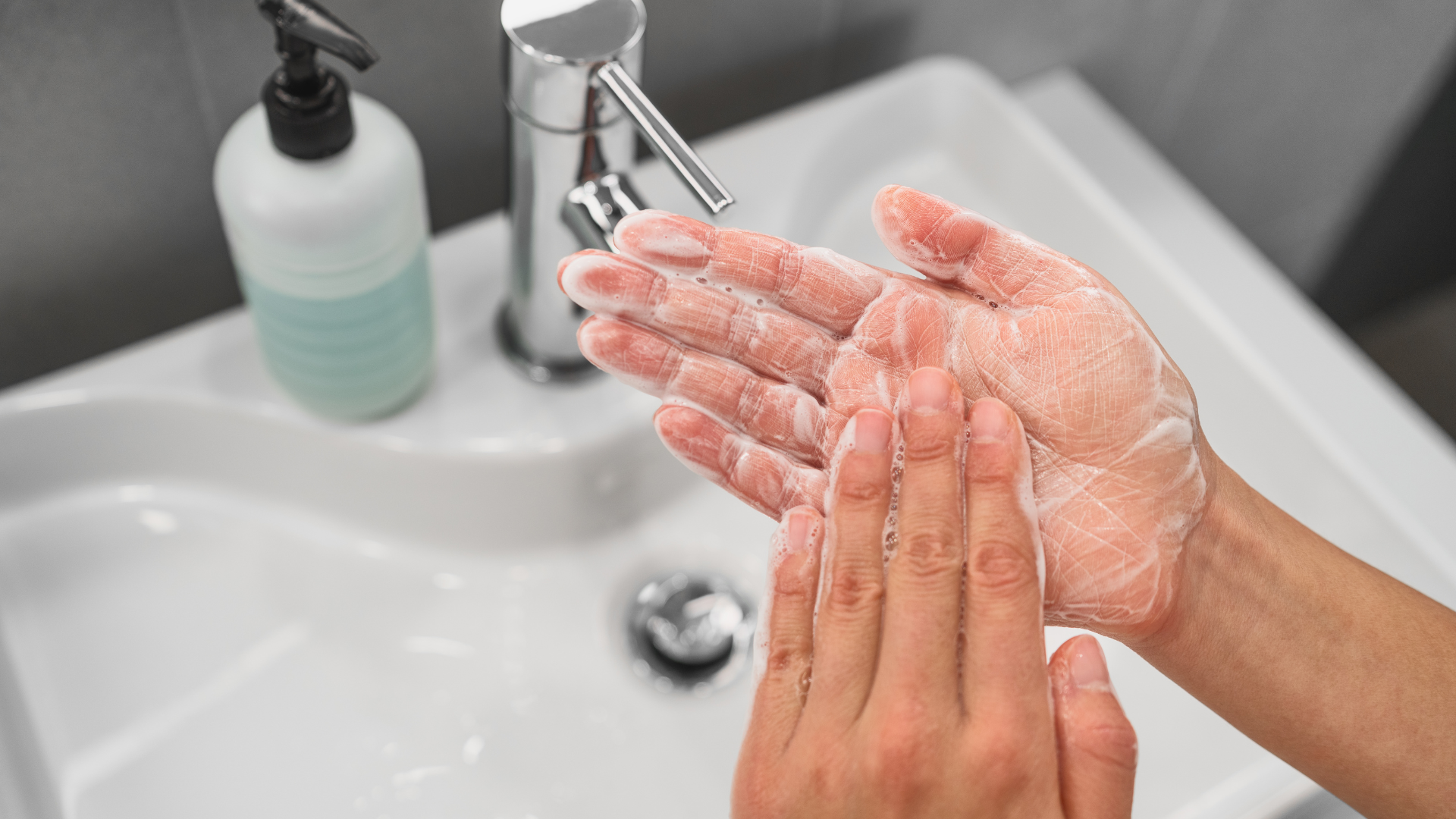 Person washing hands with soap at a sink.