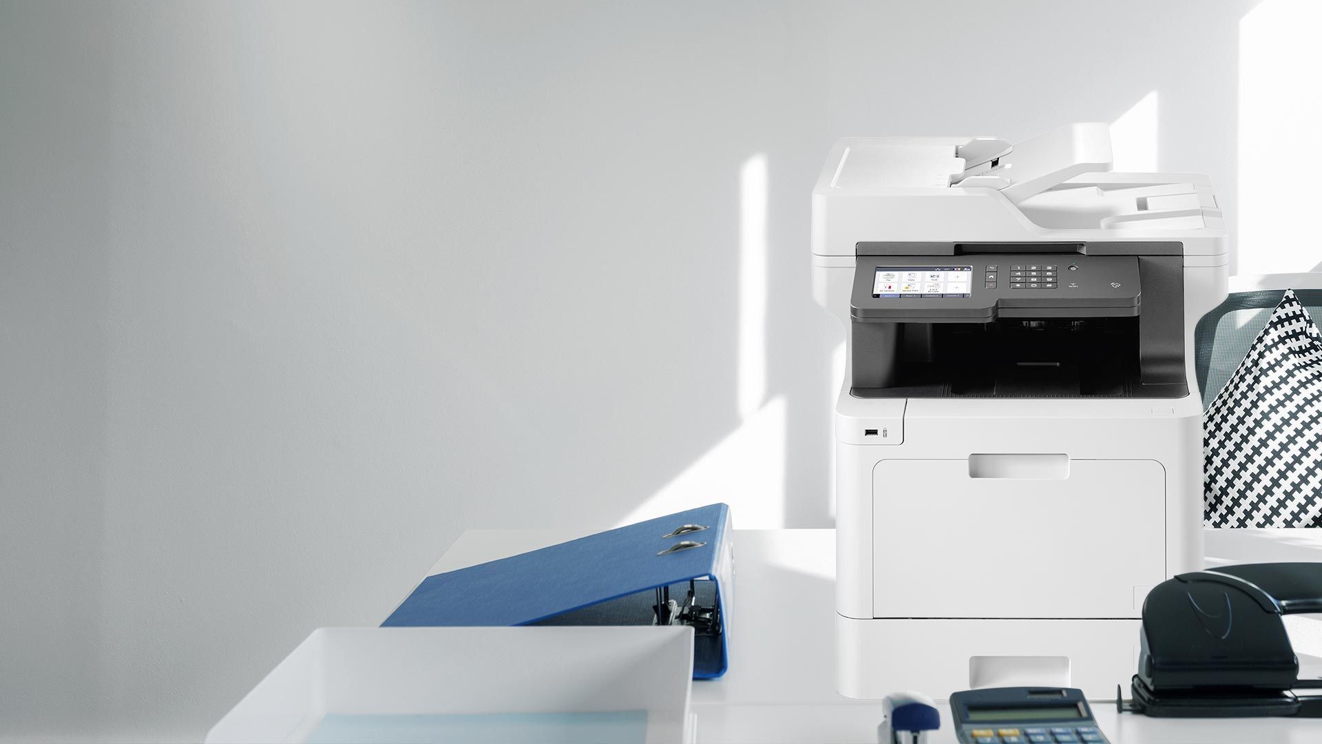 White office with a printer and office supplies on a desk.