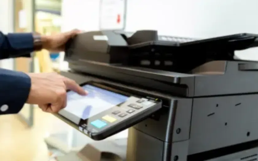 Person using the touchscreen on a black office copier.