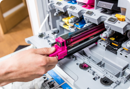 Person replacing a magenta toner cartridge in a color printer.
