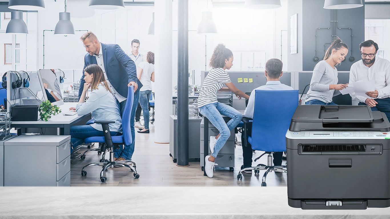 Office scene with people working at desks, a printer in foreground.