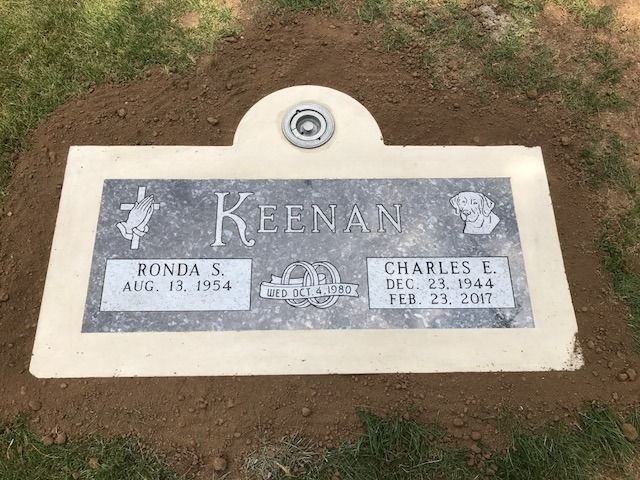 Keenan double gravestone in a grassy cemetery, with inset plaques and a central vase holder
