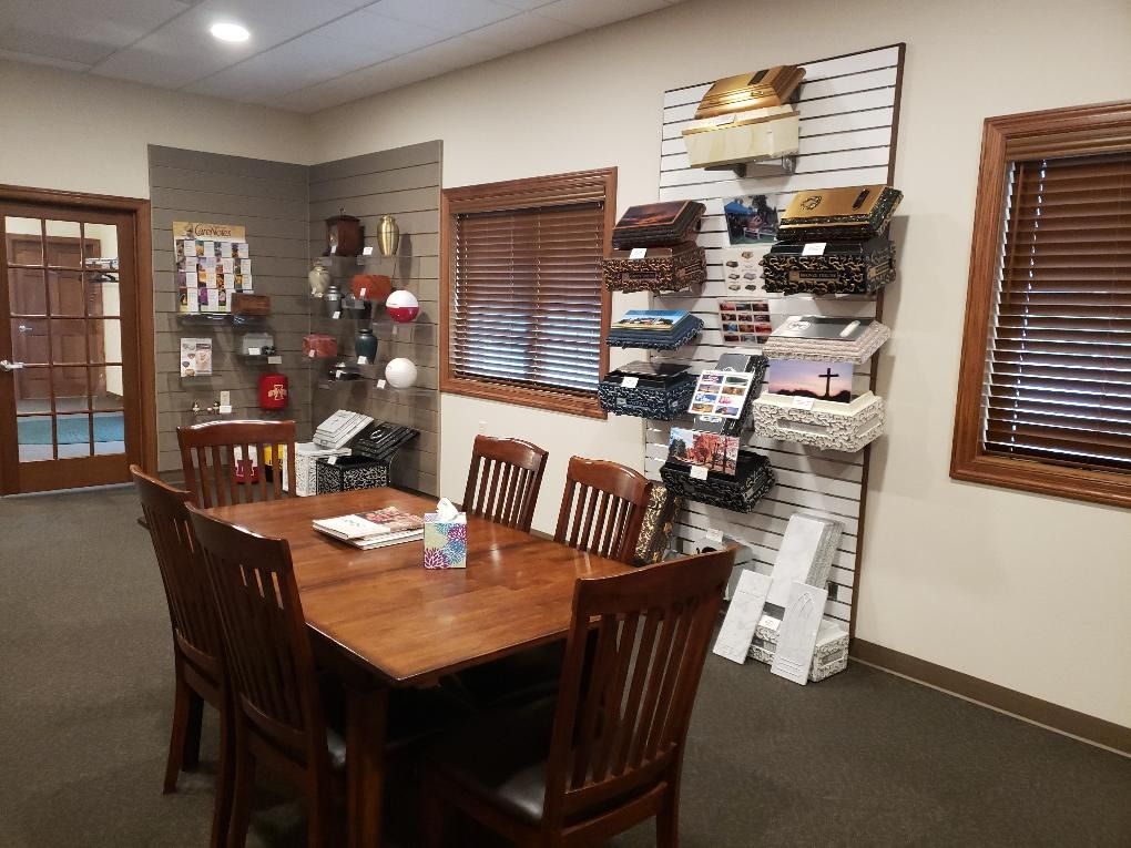 Small office waiting area with wooden table, chairs, brochure rack, and window blinds
