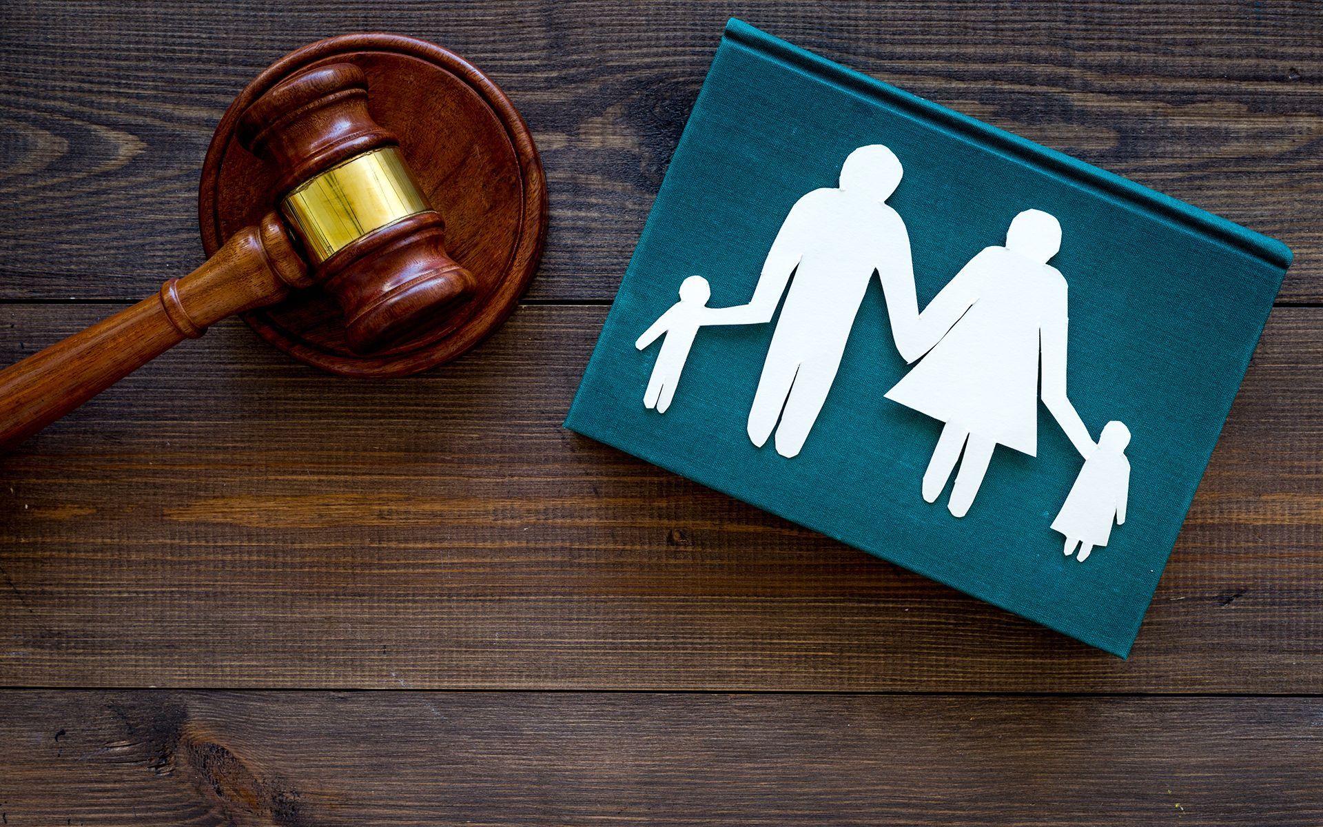 Wooden gavel beside a teal book with a family silhouette.