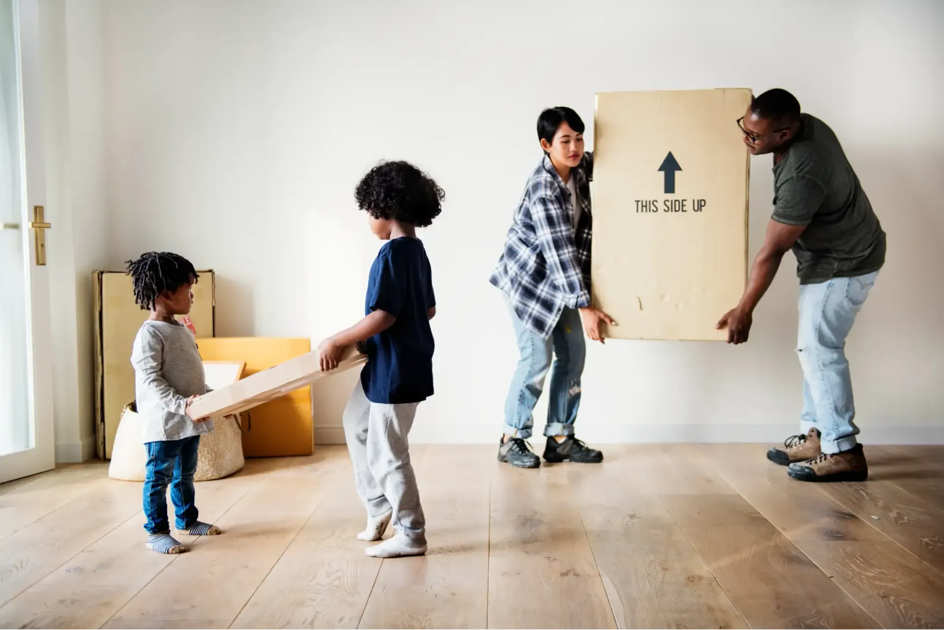 Family carrying boxes into room together