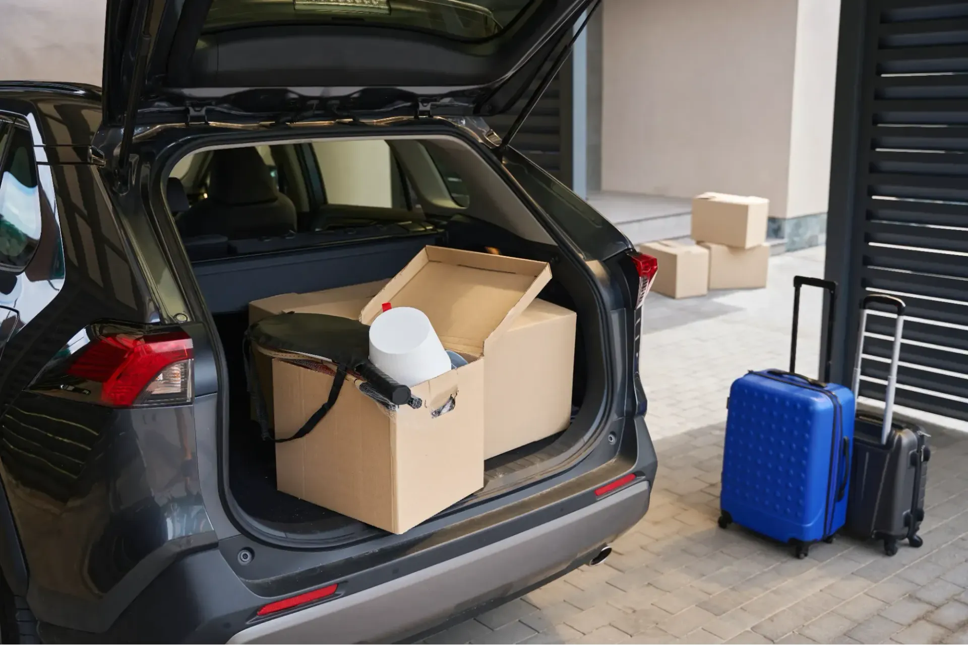 The trunk of a car is filled with boxes and luggage.