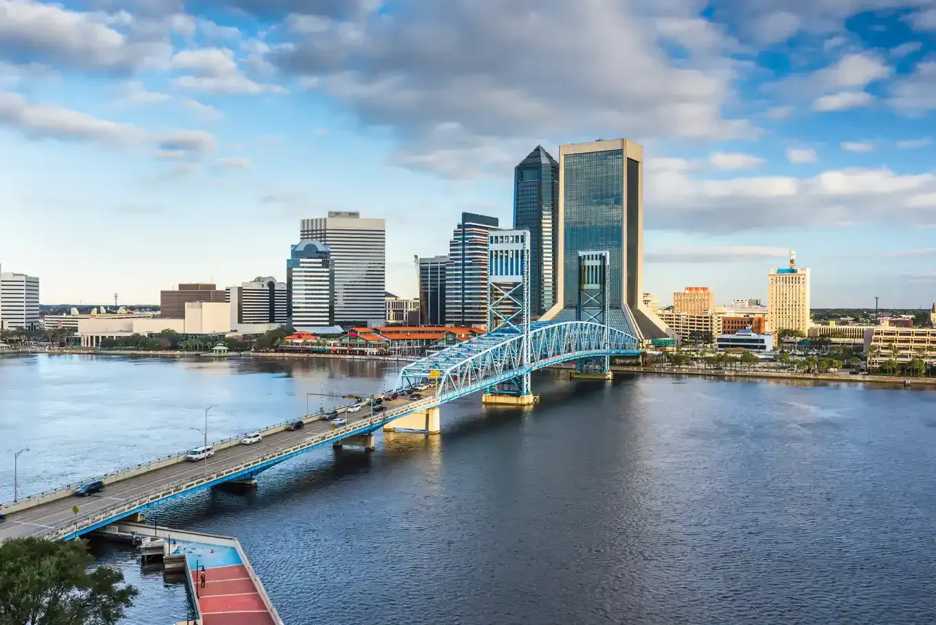 Blue bridge over river with Jacksonville, Florida skyline.