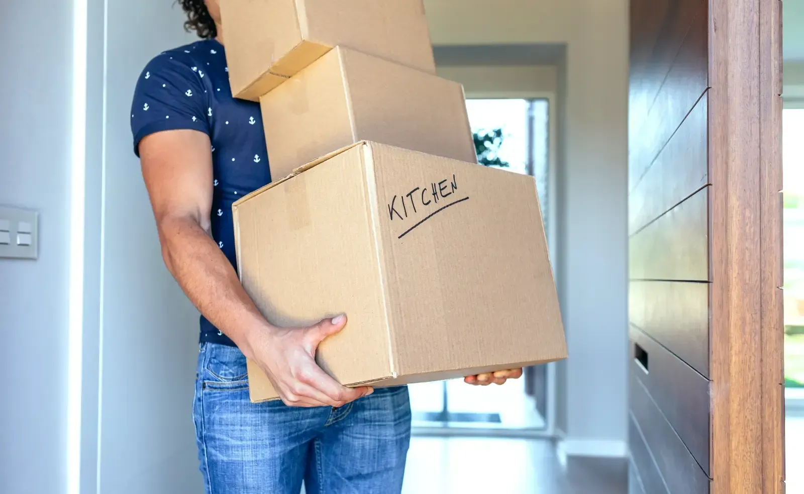 Person carrying a stack of cardboard boxes labeled