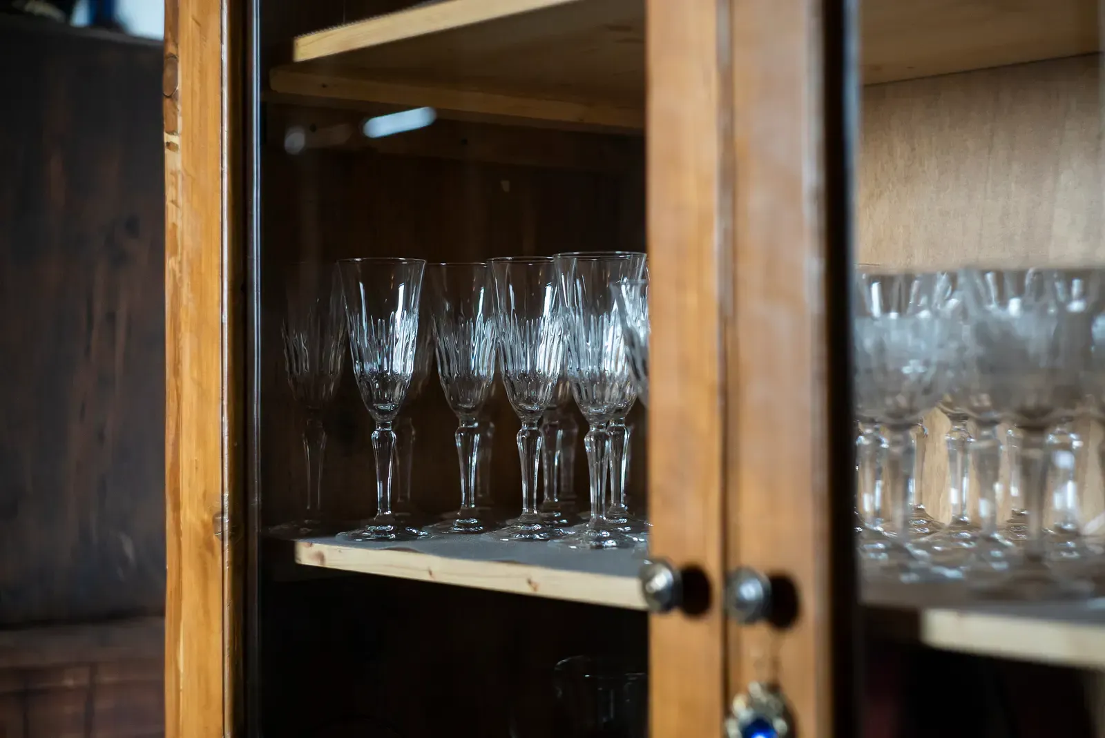 Crystal stemware displayed inside a wooden cabinet with glass doors.