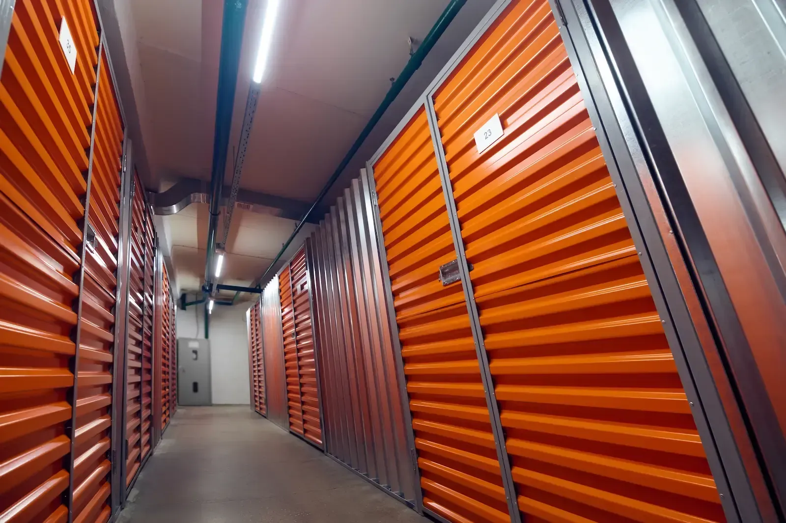 Orange storage units lined up in a well-lit indoor corridor.